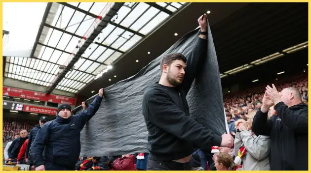 Liverpool fans prepare to unfurl a banner objecting to ticket price increases at Anfield