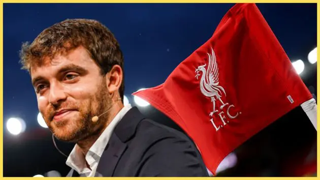Fabrizio Romano smiles next to Liverpool flag.