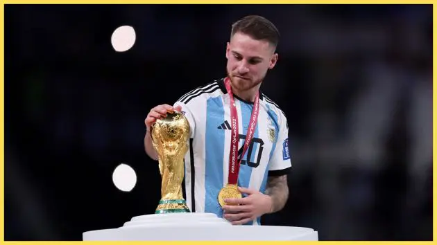 Liverpool midfielder Alexis Mac Allister places his hand on the World Cup trophy.